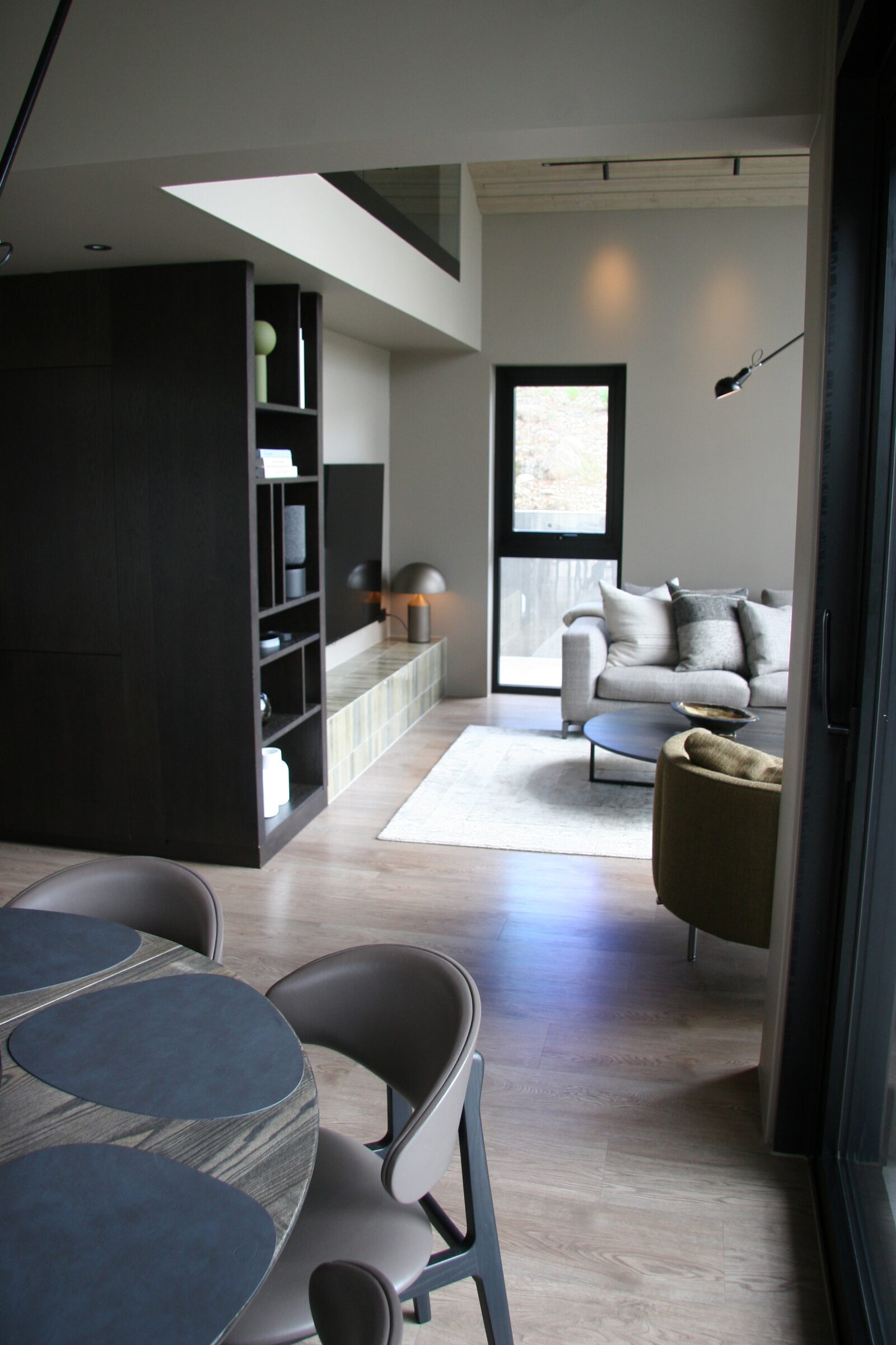 A view down a hallway past dining chairs toward a bright living room with a light sofa.