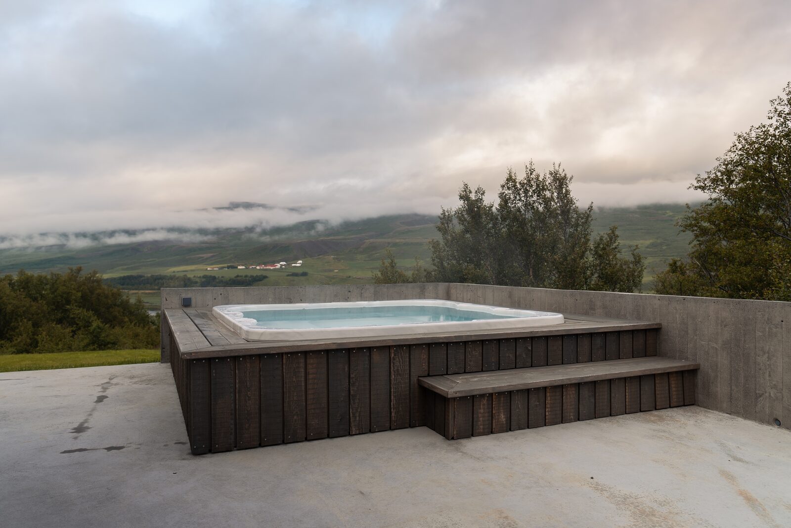 The hot tub and terrace under an overcast sky, the valley stretching out behind.