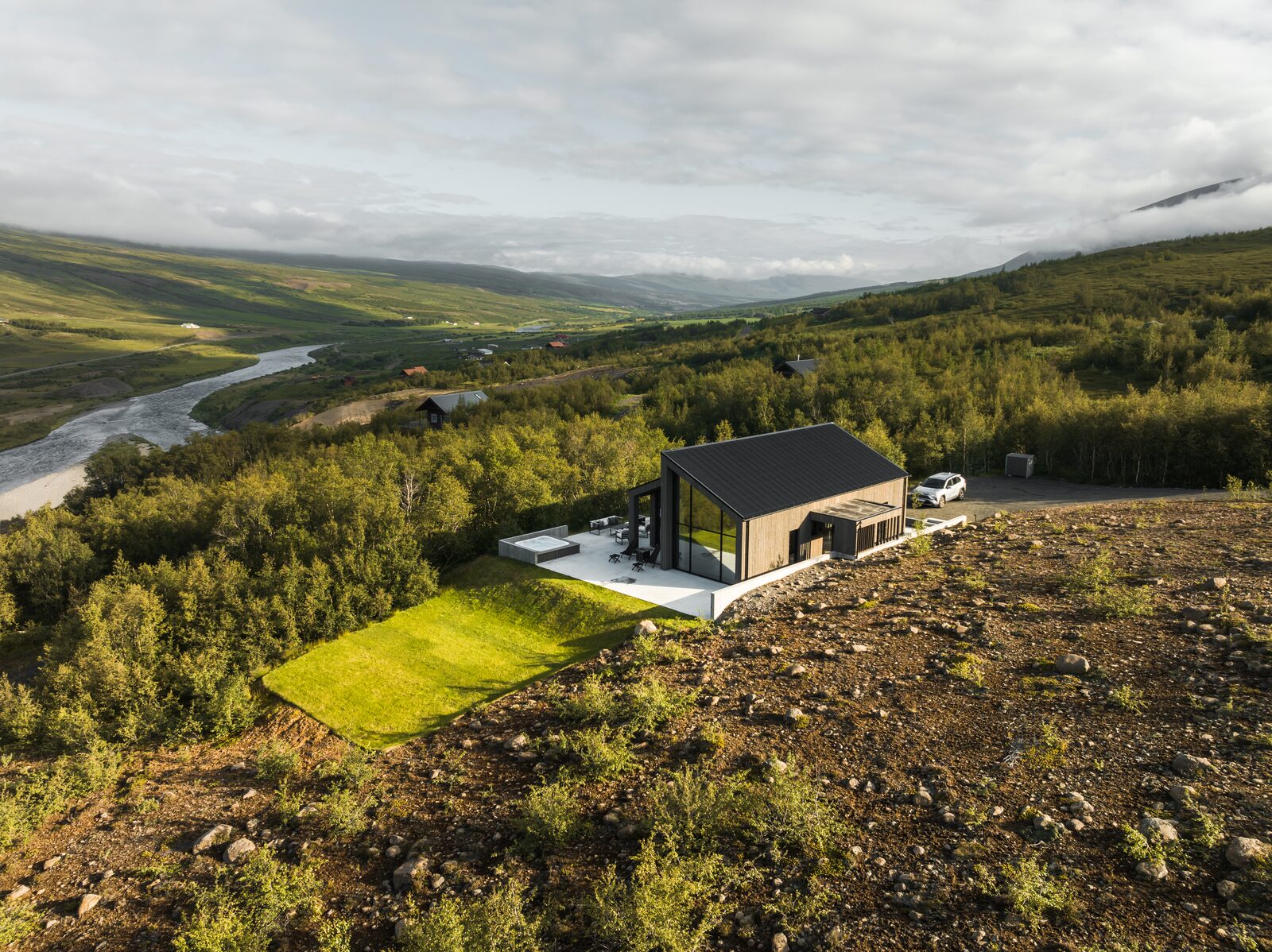 A drone view over the broader Fnjóskadalur valley and the river Fnjóská, with the house small in the landscape.