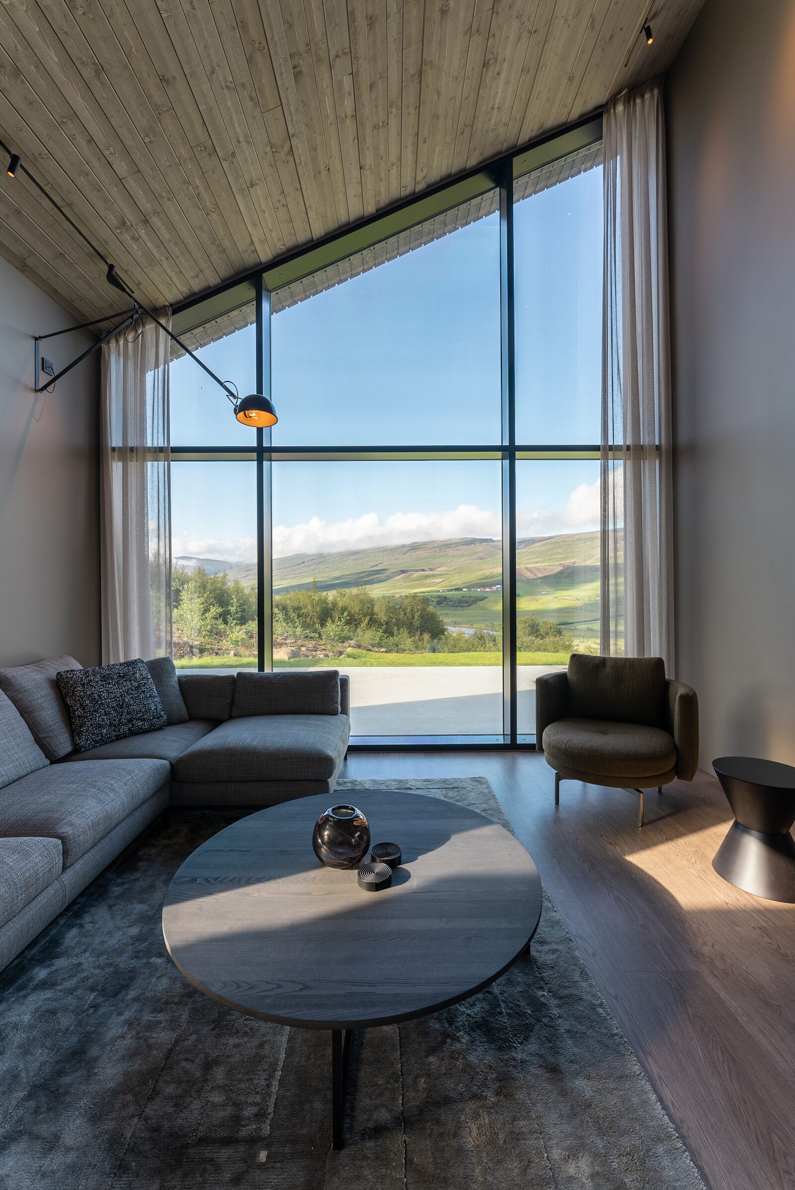 The living room's seating area from a portrait-oriented angle, sofa and armchairs around the coffee table.